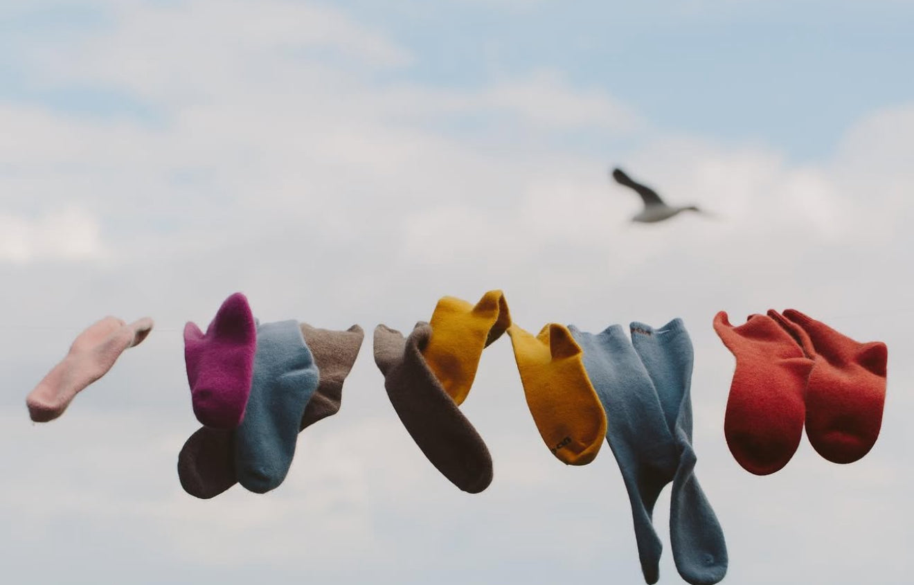 Colourful possum merino socks hanging on a line against a sky