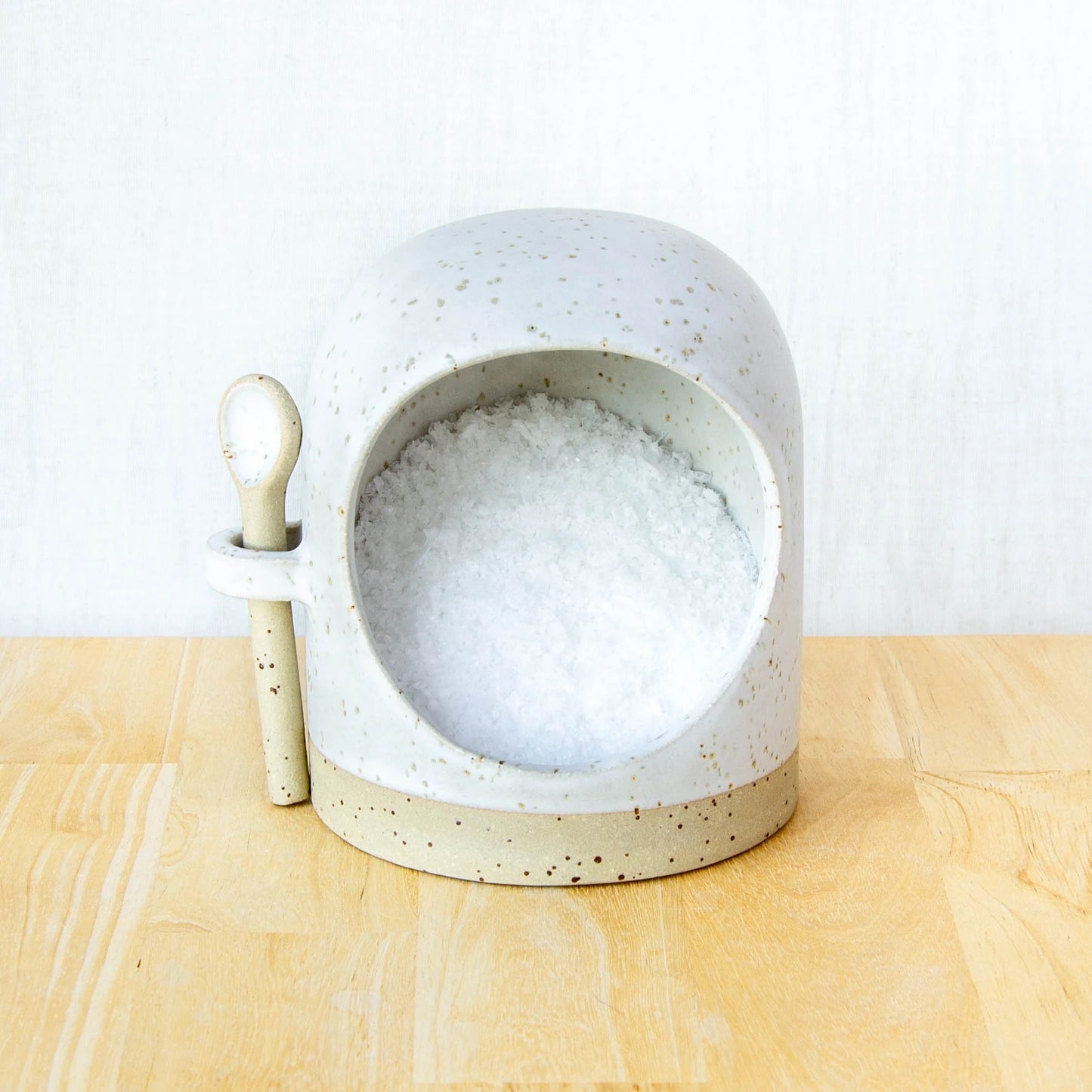 Ceramic salt pig with spoon in oat white glaze on wooden surface