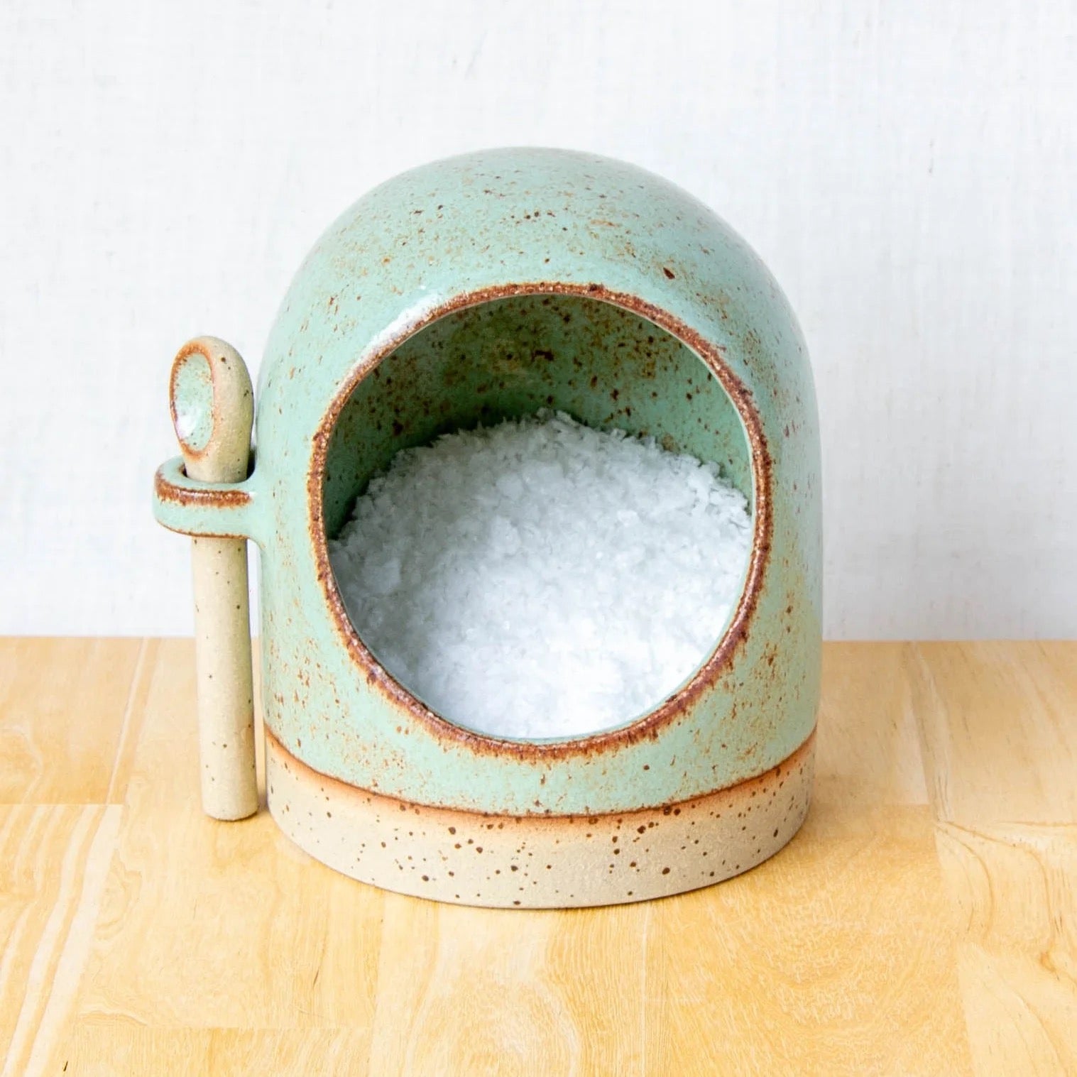 Ceramic salt pig with spoon in light green glaze close-up